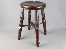 A wooden stool on turned supports.