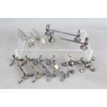 Five pairs of white metal and silver plated knife rests of varying form.