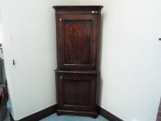 A floor standing oak corner cupboard with shelved interior,