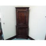 A floor standing oak corner cupboard with shelved interior,