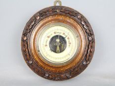 An oak cased barometer with oak leaf carved detail,