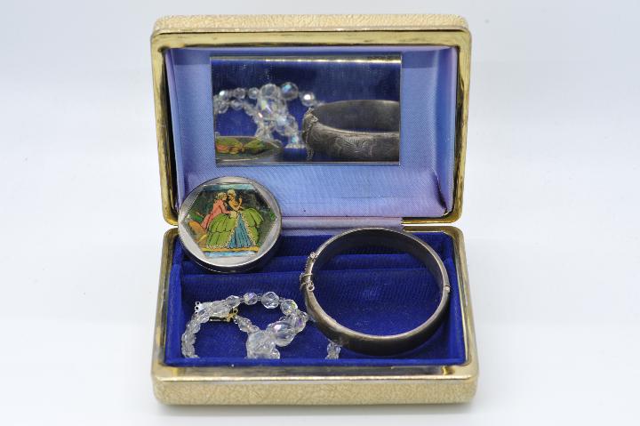 A vintage jewellery box containing a hallmarked silver bangle with safety chain,