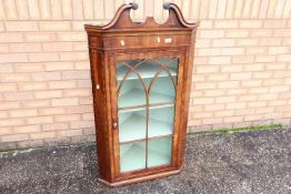 A George III mahogany bow-fronted hanging corner cupboard with broken swan-neck pediment above an