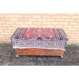 A wooden chest with wool rug nailed to the cover,
