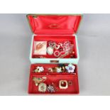 A jewellery box containing a quantity of brooches, paired earrings,