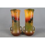 Royal Doulton - A set of two twin handled, elongated vases decorated with rural cottage scenes,
