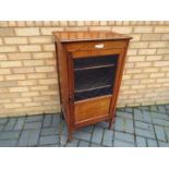 An Edwardian mahogany cabinet, the glazed door opening to reveal a four-tier shelved interior,