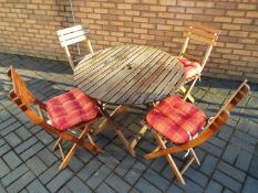 Garden Furniture - A wooden folding garden table measuring 90cm diameter plus four folding wooden