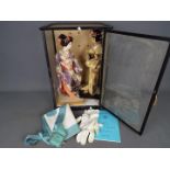 Two dolls in traditional Japanese dress contained in a display case approximately 49 cm x 33 cm x
