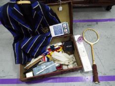 A vintage suitcase containing a mixed lot of collectables to include vintage tennis racket, flags,