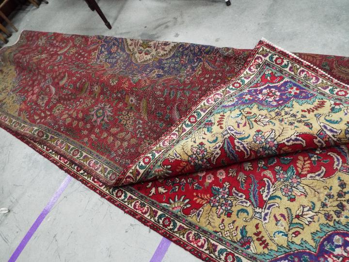 A polychrome Persian Tabarese carpet measuring approximately 328 cm x 232 cm