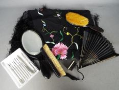 An ebony dressing table set comprising mirror and two brushes, a paper fan,