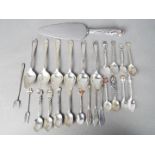 A collection of flatware to include silver handled cake slice, a quantity of spoons,