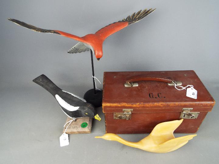 A vintage, leather case of small form and three carved bird figurines.