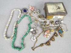 A small metal box and contents of assorted costume jewellery,