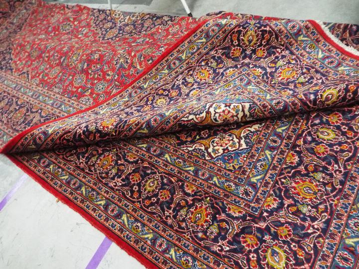 A large red ground Persian Kashan carpet measuring approximately 290 cm x 400 cm