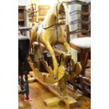 Varnished wood rocking horse on safety stand, 98cm by 111cm.