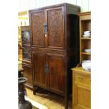 Chinese four door cabinet, the upper doors having carved panels, 214cm by 109cm.