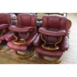 Pair Ekornes Stressless burgundy leather adjustable swivel chairs and footstools.