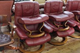Pair Ekornes Stressless burgundy leather adjustable swivel chairs and footstools.