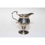 Silver helmet style cream jug embossed with swags and flower heads, marks worn.