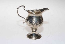 Silver helmet style cream jug embossed with swags and flower heads, marks worn.
