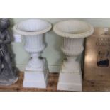 Pair cast campana style garden urns on plinth bases, 66cm by 38cm.