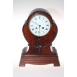 Shaped mahogany mantel clock raised on bracket feet with enamelled and Roman numeral dial.