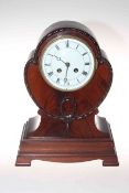 Shaped mahogany mantel clock raised on bracket feet with enamelled and Roman numeral dial.