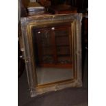 Rectangular swept gilt frame bevelled wall mirror, 118cm by 88cm overall.