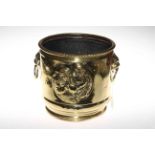 Embossed brass jardiniere with lion mask ring handles.