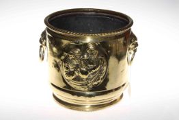 Embossed brass jardiniere with lion mask ring handles.