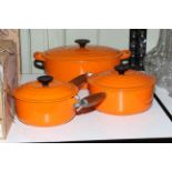 Le Creuset cookware including two pans and casserole dish.