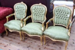 Set of three gilt painted fauteuils in green buttoned fabric.