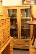 Contemporary light oak display cabinet having two glazed doors above two long drawers,