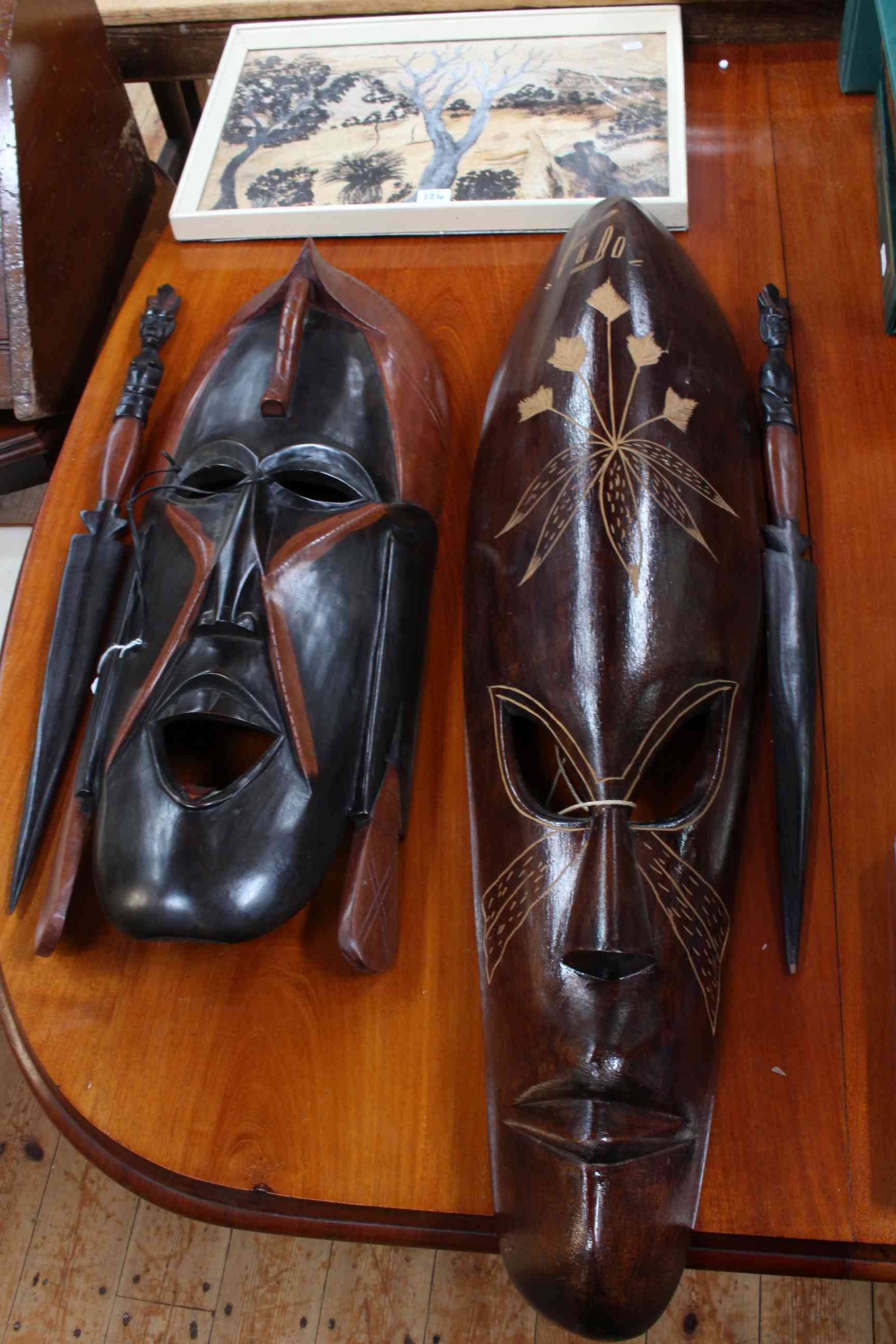 Two tribal wooden masks, a pair of tribal spears together with a aboriginal painting.
