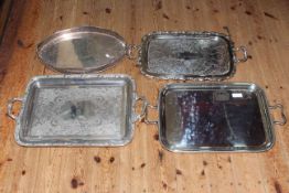 Four silver plated serving trays with handles.