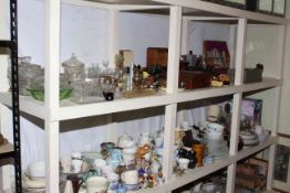 Two full shelves of china, glass, canteen of cutlery, clocks, dolls, toilet bottles, etc.