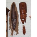 Collection of tribal masks and heavily carved wood panel.