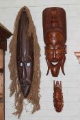 Collection of tribal masks and heavily carved wood panel.