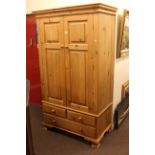 Pine combination wardrobe having two panelled doors above two short and one long drawer,