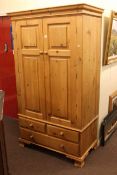 Pine combination wardrobe having two panelled doors above two short and one long drawer,