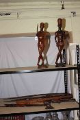 Collection of carved tribal wood carvings including spears, spoon, statues, etc.