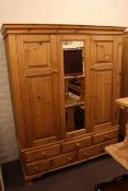 Pine combination wardrobe having central mirror panel flanked by two panelled doors above three