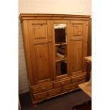 Pine combination wardrobe having central mirror panel flanked by two panelled doors above three