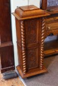 Late 19th/early 20th Century slim oak cabinet having two carved panel doors with twist pillars,