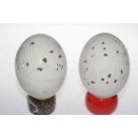 Two carved ostrich eggs on stands.