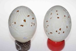 Two carved ostrich eggs on stands.