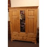 Pine combination wardrobe having central mirror panel flanked by two panelled doors above three