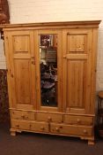 Pine combination wardrobe having central mirror panel flanked by two panelled doors above three